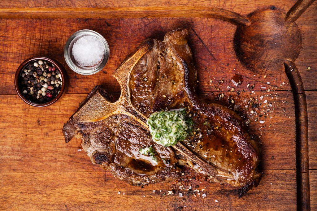 Grilled T-Bone Steak and herb butter on wooden cutting board