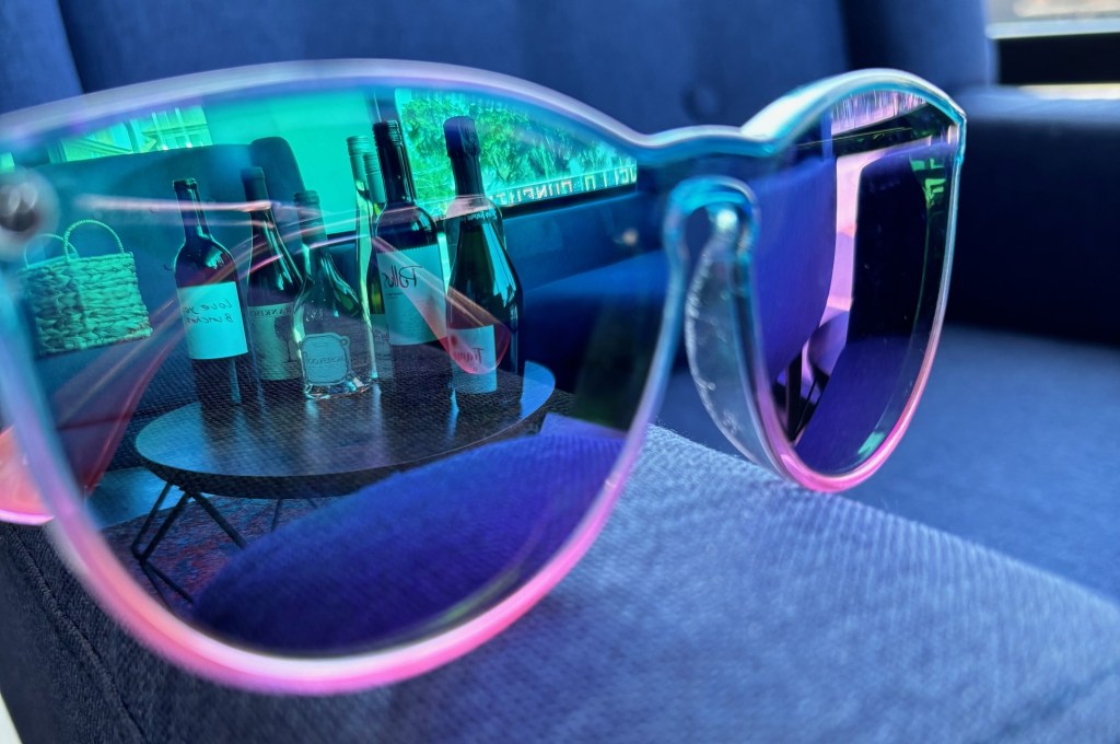 A group of wine bottles on a table, through the lens of sunglasses